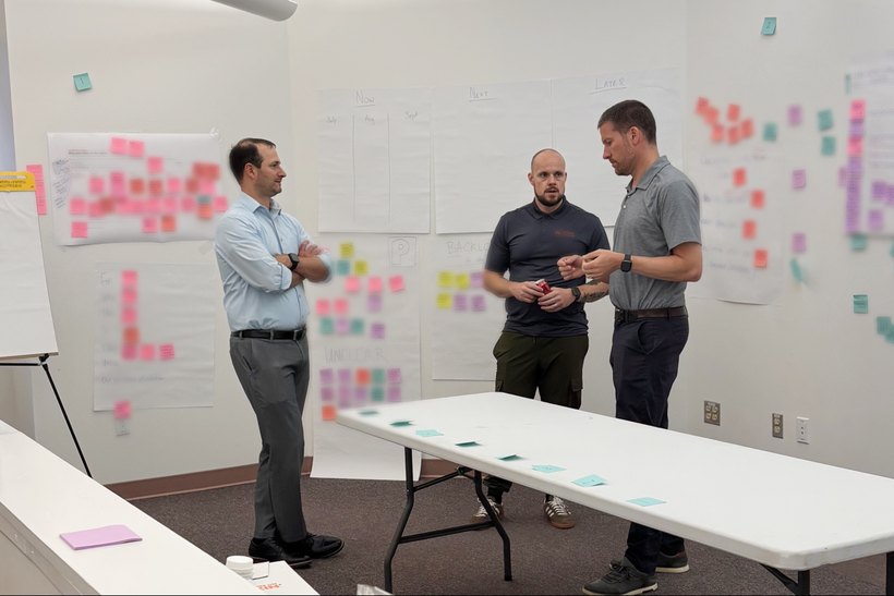 Leadership team building a portfolio Kanban with a Now / Next / Later wall of sticky notes during a three-day strategy execution workshop